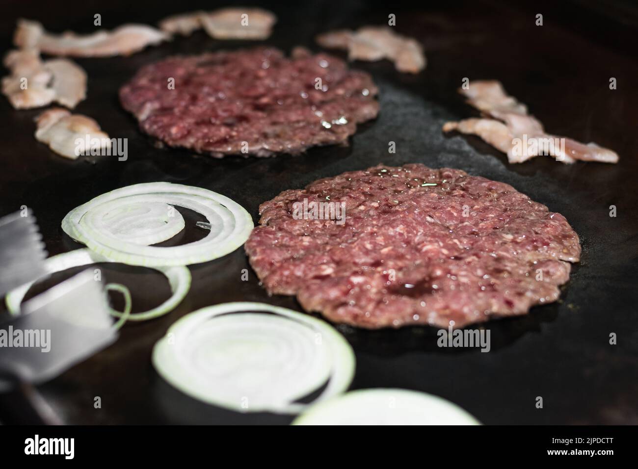 dettaglio primo piano di due hamburger macinati con cipolla e tosino intorno, cucina in uno street food colombiano grill o fast food stand, manzo su Foto Stock