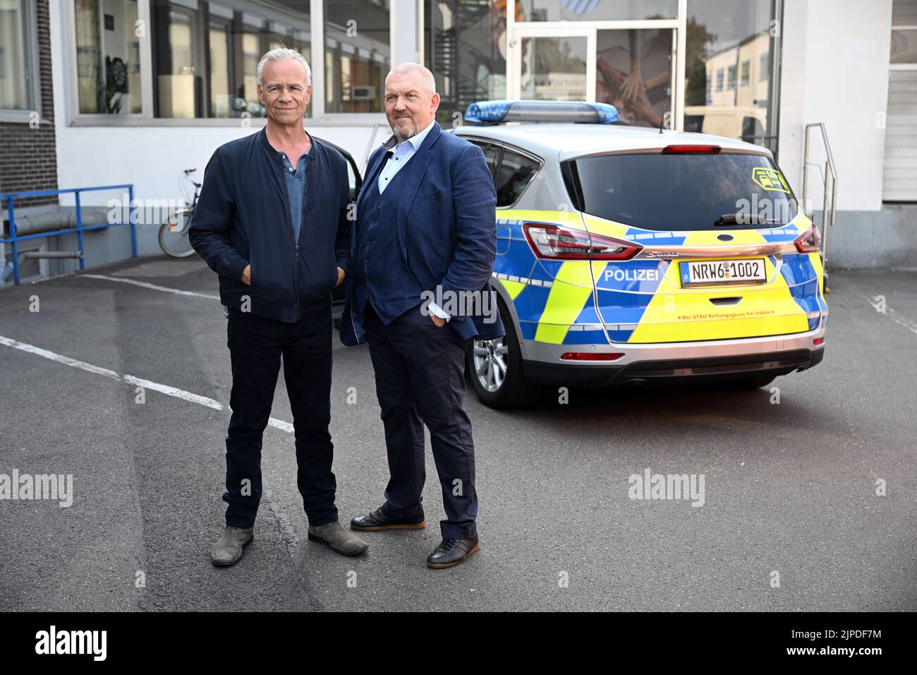 Colonia, Germania. 17th ago, 2022. Gli attori Klaus J. Behrendt (l) come Max Ballauf e Dietmar Bär (r) come Freddy Schenk stanno davanti a una macchina della polizia sul set. Sono iniziate le riprese per il 'Tatort' 88th di Colonia. L'episodio sarà mostrato nel 2023 in TV tedesca. Credit: Federico Gambarini/dpa/Alamy Live News Foto Stock