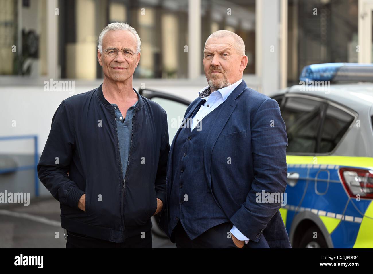 Colonia, Germania. 17th ago, 2022. Gli attori Klaus J. Behrendt (l) come Max Ballauf e Dietmar Bär (r) come Freddy Schenk stanno davanti a una macchina della polizia sul set. Sono iniziate le riprese per il 'Tatort' 88th di Colonia. L'episodio sarà mostrato nel 2023 in TV tedesca. Credit: Federico Gambarini/dpa/Alamy Live News Foto Stock