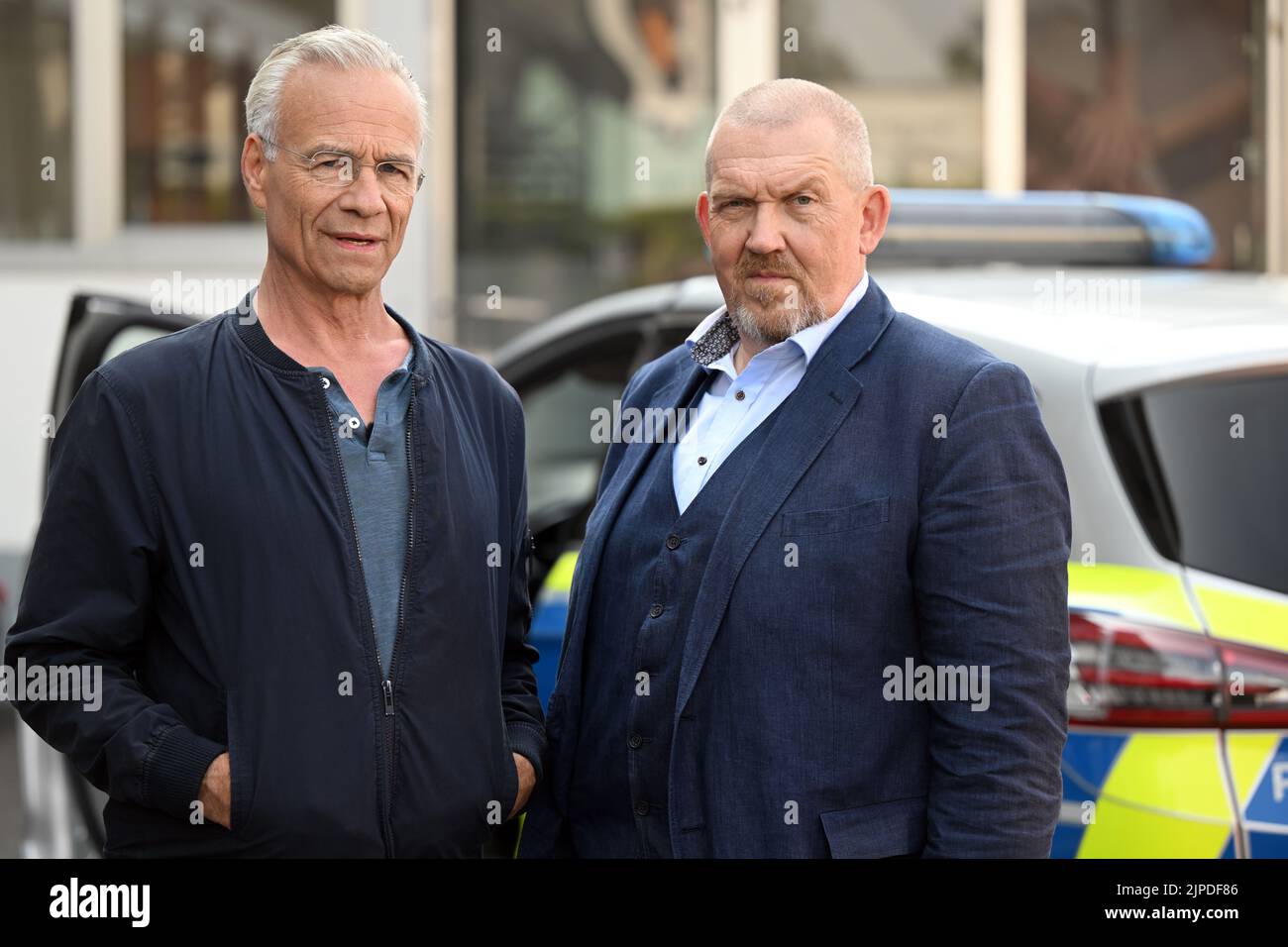Colonia, Germania. 17th ago, 2022. Gli attori Klaus J. Behrendt (l) come Max Ballauf e Dietmar Bär (r) come Freddy Schenk stanno davanti a una macchina della polizia sul set. Sono iniziate le riprese per il 'Tatort' 88th di Colonia. L'episodio sarà mostrato nel 2023 in TV tedesca. Credit: Federico Gambarini/dpa/Alamy Live News Foto Stock