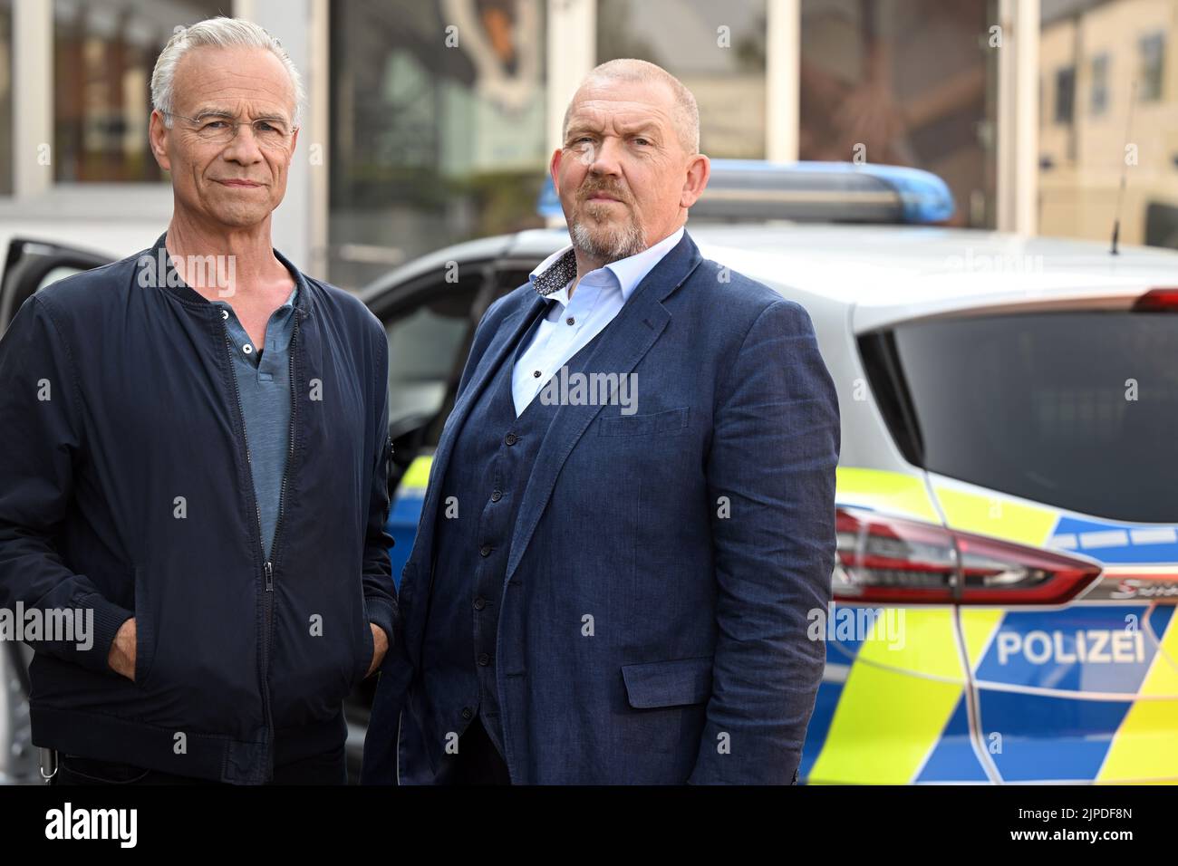 Colonia, Germania. 17th ago, 2022. Gli attori Klaus J. Behrendt (l) come Max Ballauf e Dietmar Bär (r) come Freddy Schenk stanno davanti a una macchina della polizia sul set. Sono iniziate le riprese per il 'Tatort' 88th di Colonia. L'episodio sarà mostrato nel 2023 in TV tedesca. Credit: Federico Gambarini/dpa/Alamy Live News Foto Stock