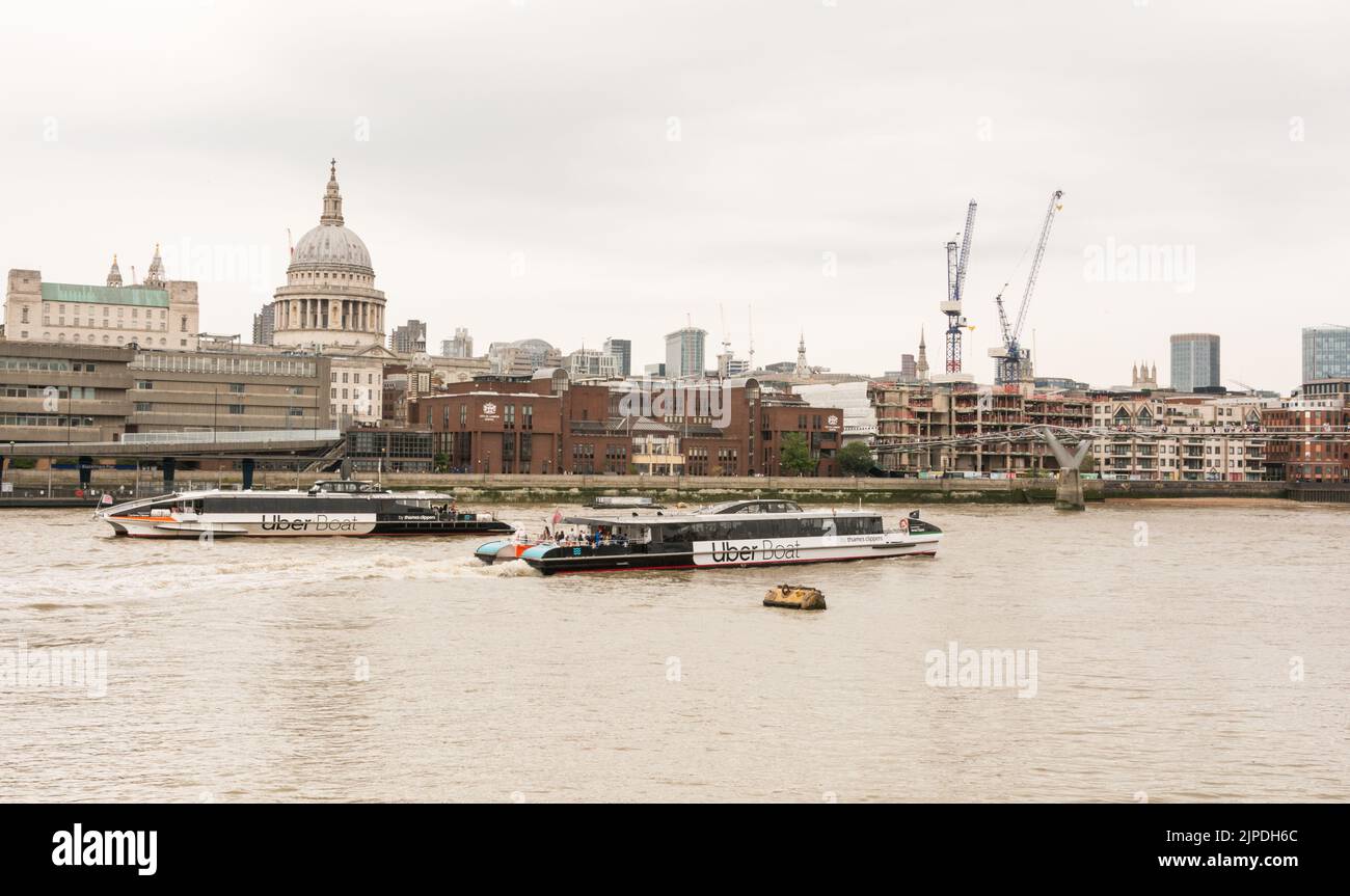 Due barche Uber che passano davanti alla Cattedrale di St Paul e alla City of London School sulla northbank del Tamigi, Londra, Inghilterra, Regno Unito Foto Stock
