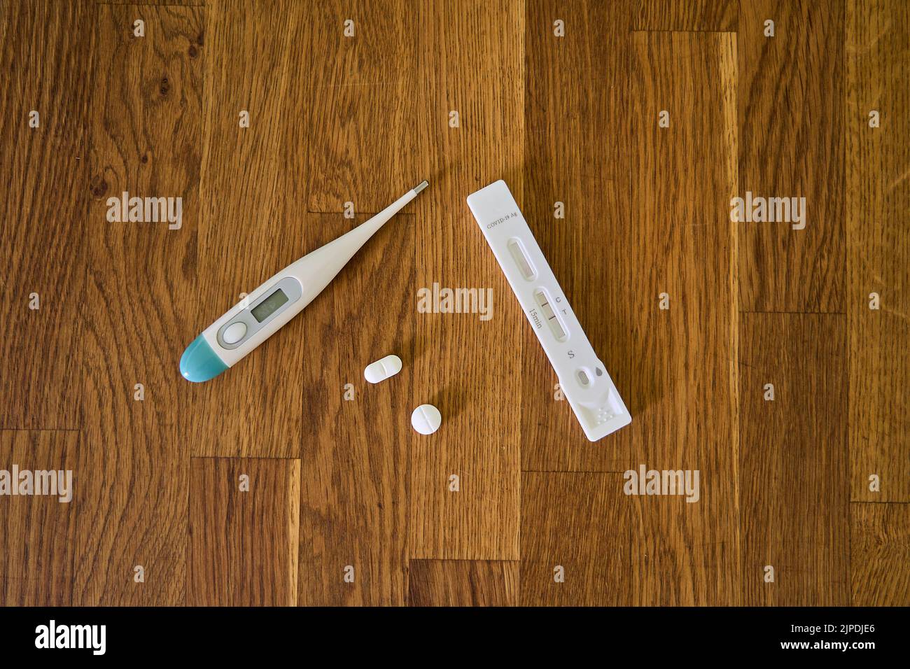 Test di scorrimento della corona positivo che mostra due barre per l'infezione da Covid 19 insieme al farmaco e al termometro clinico Foto Stock