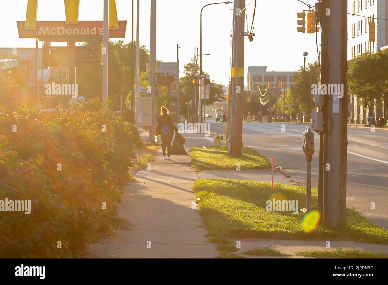 Kalamazoo, Michigan - una donna apparentemente senza casa trasporta gli effetti personali in una borsa di spazzatura mentre cammina per le strade al mattino presto. Foto Stock