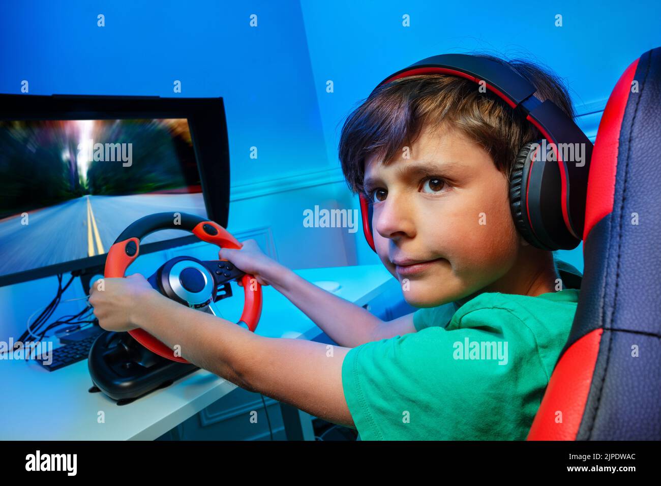Ragazzo con volante gioco di gara girare e guardare indietro Foto Stock