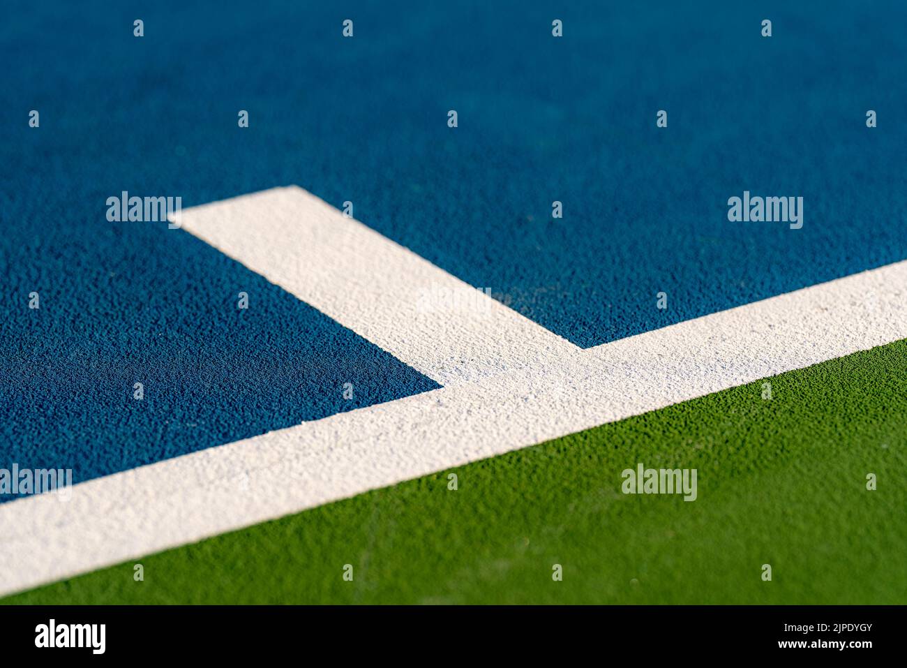 Foto ravvicinata del segno centrale alla base di un nuovo campo da tennis blu all'aperto con linee bianche. Foto Stock