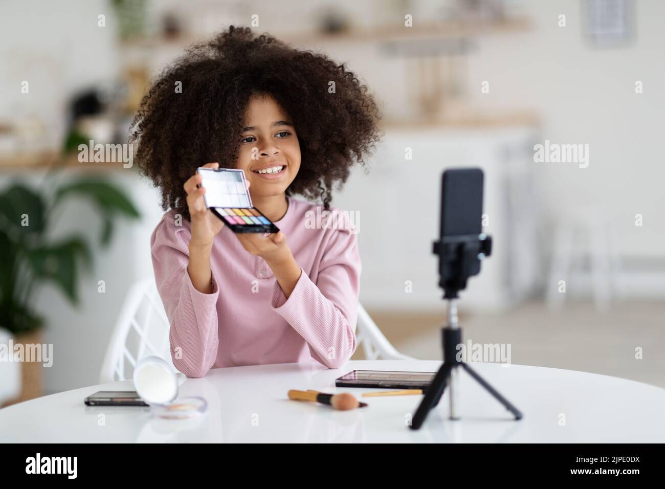 Ragazza pre-teen nera che fa trucco e registrazione vlog sul telefono Foto Stock