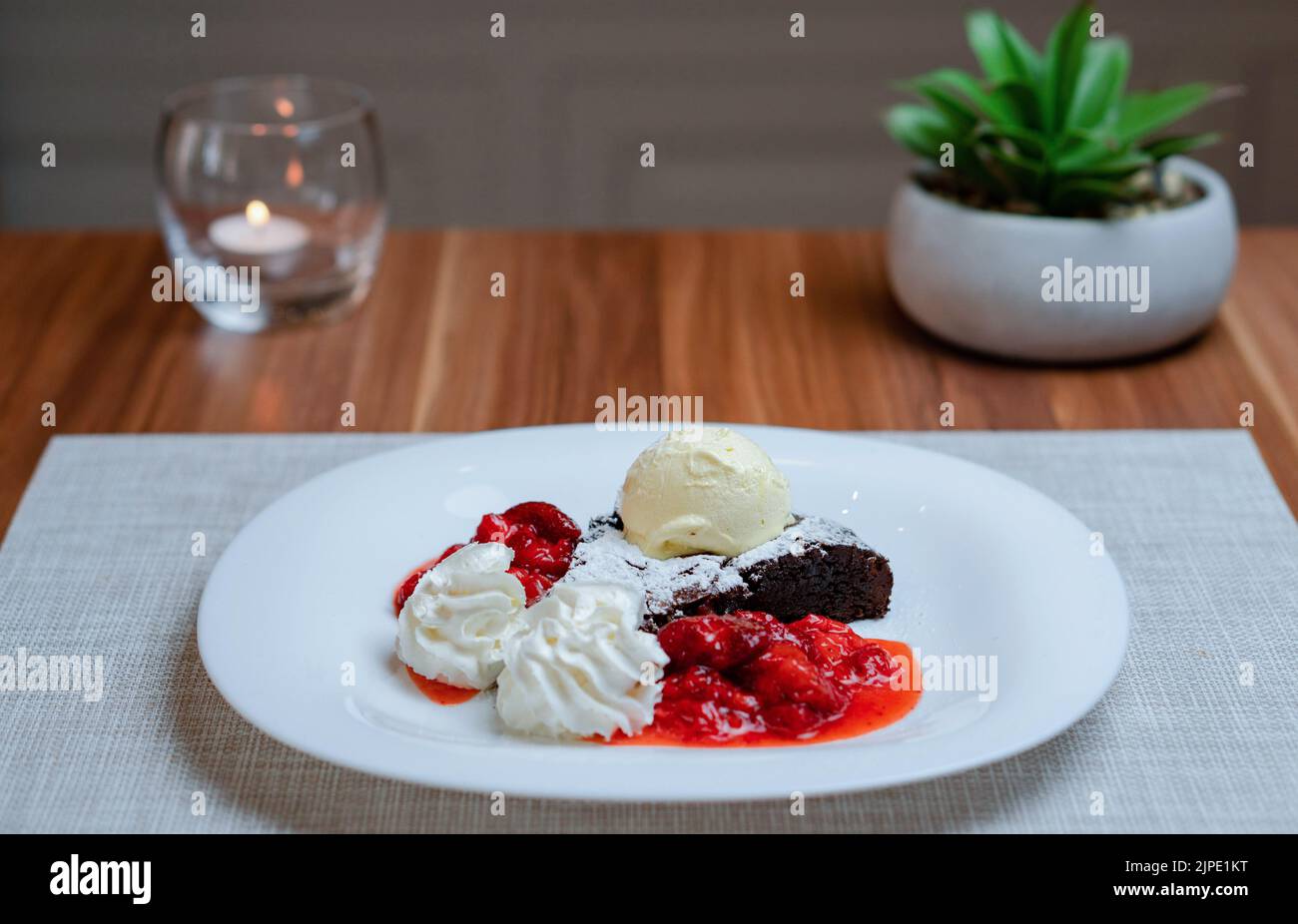 Brownie con cioccolato fondente, panna montata, gelato e purea di fragole Foto Stock