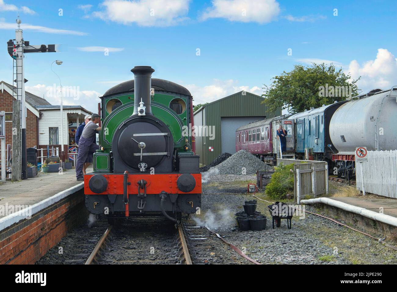 Gli autisti del treno chiacchierano accanto al motore a vapore alla piattaforma con il segnale nella stazione ferroviaria di Lincolnshire Wolds Railway, Ludborough, Inghilterra, Regno Unito Foto Stock