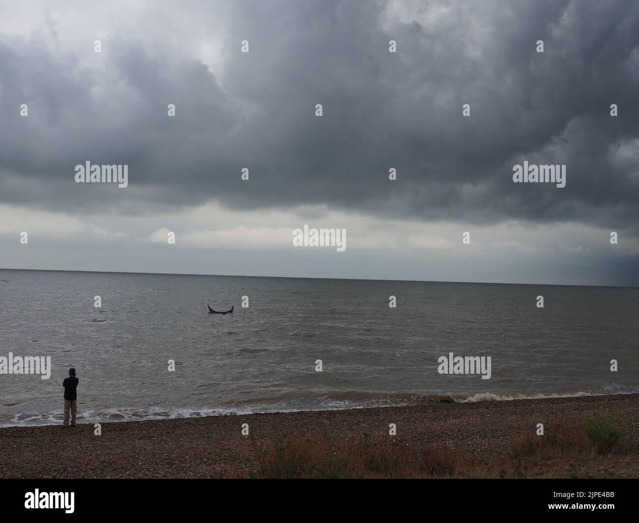 Minster on Sea, Kent, Regno Unito. 17th ago, 2022. UK Weather: Un kite surfer sembrava essere in difficoltà proprio come le nuvole di tempesta hanno rotolato su Minster sul lungomare di mare questo pomeriggio. Il kite surfer è stato incontrato dalla guardia costiera e da un bagnino. Il kite surfer swam la loro tavola e kite di nuovo a riva dopo aver sperimentato le difficoltà. La scialuppa di salvataggio costiera fu lanciata, ma il kite surfer riuscì a riportarla a riva da solo. Credit: James Bell/Alamy Live News Foto Stock