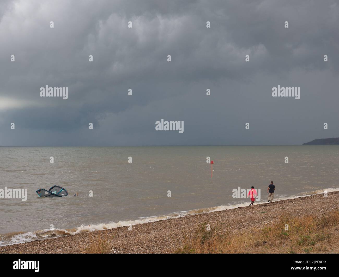 Minster on Sea, Kent, Regno Unito. 17th ago, 2022. UK Weather: Un kite surfer sembrava essere in difficoltà proprio come le nuvole di tempesta hanno rotolato su Minster sul lungomare di mare questo pomeriggio. Il kite surfer è stato incontrato dalla guardia costiera e da un bagnino. Il kite surfer swam la loro tavola e kite di nuovo a riva dopo aver sperimentato le difficoltà. La scialuppa di salvataggio costiera fu lanciata, ma il kite surfer riuscì a riportarla a riva da solo. Credit: James Bell/Alamy Live News Foto Stock