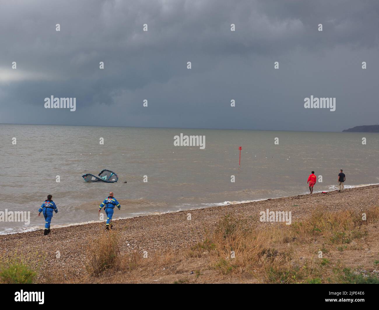 Minster on Sea, Kent, Regno Unito. 17th ago, 2022. UK Weather: Un kite surfer sembrava essere in difficoltà proprio come le nuvole di tempesta hanno rotolato su Minster sul lungomare di mare questo pomeriggio. Il kite surfer è stato incontrato dalla guardia costiera e da un bagnino. Il kite surfer swam la loro tavola e kite di nuovo a riva dopo aver sperimentato le difficoltà. La scialuppa di salvataggio costiera fu lanciata, ma il kite surfer riuscì a riportarla a riva da solo. Credit: James Bell/Alamy Live News Foto Stock