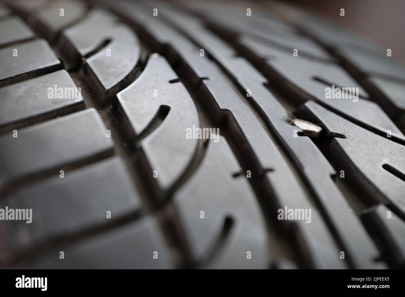 Testa di punta metallica su pneumatico piatto macro vista ravvicinata su sfondo sfocato Foto Stock