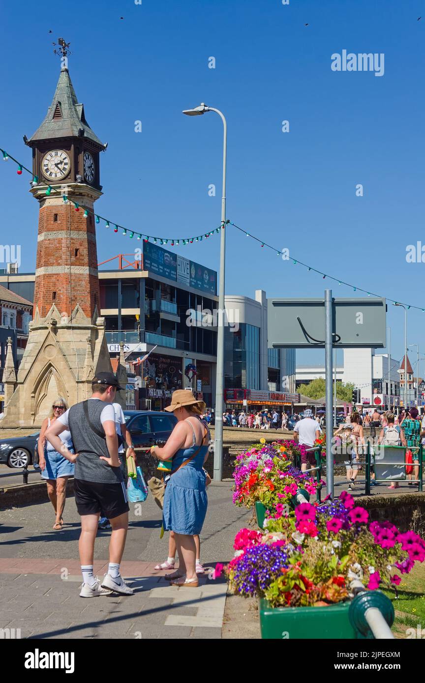 La torre dell'orologio vicino a South sfilano con folle di persone che godono di servizi durante il sole a Skegness Foto Stock