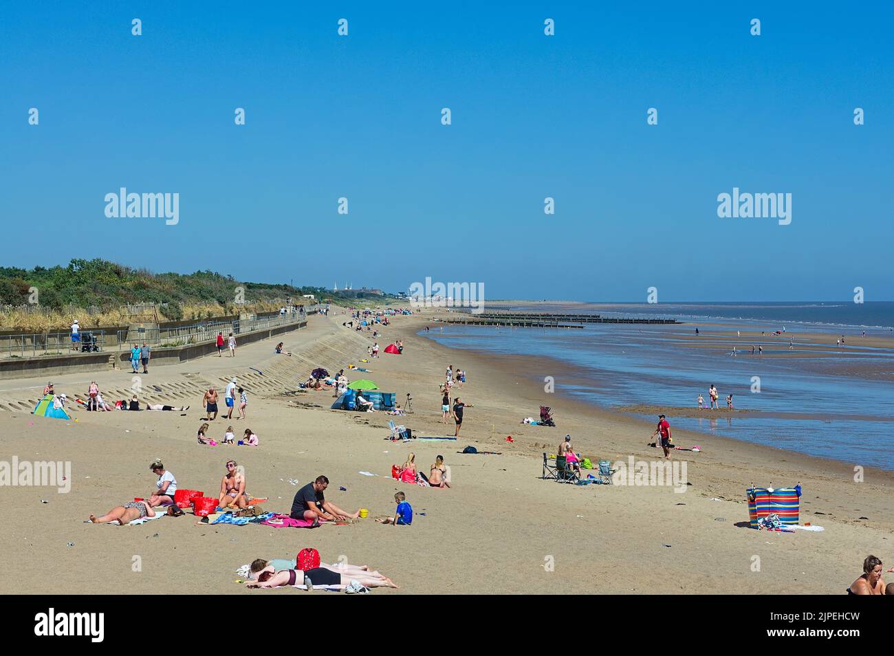 Persone che si rilassano sulla spiaggia in una calda giornata di sole a Skegness Foto Stock