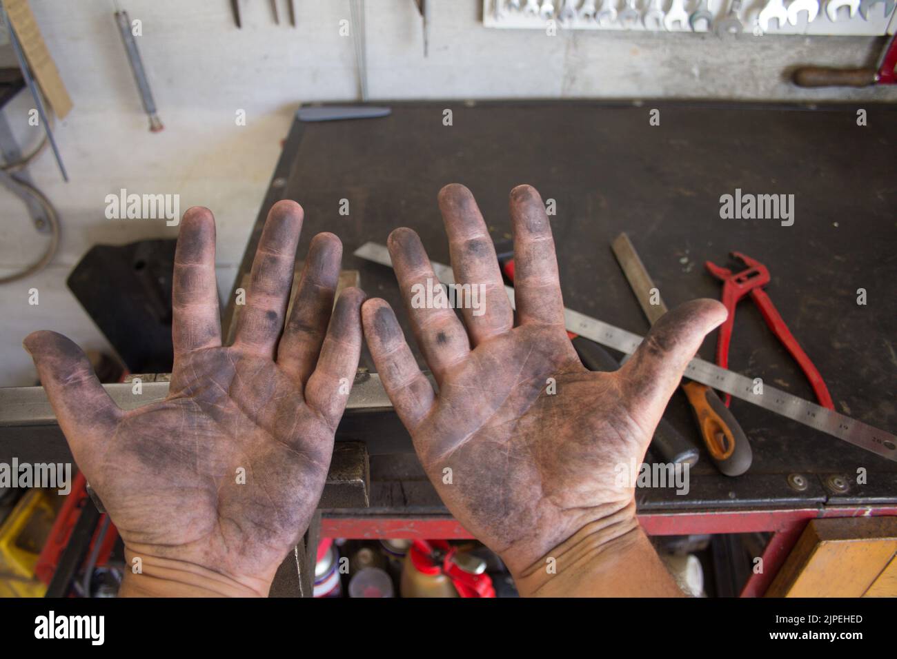 Immagine delle mani sporche di un fabbro che lavora nella sua officina con gli strumenti del background commerciale. Fai da te il lavoro. Mani sporche odore di scavo Foto Stock