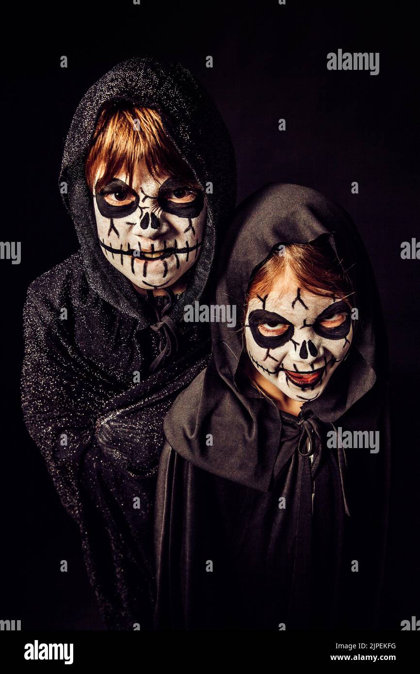 Due bambini che indossano abiti scuri e una spaventosa pittura facciale ad Halloween. Foto Stock