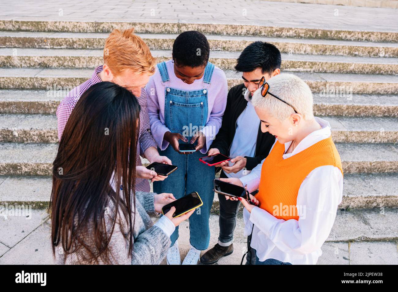 gruppo di amici che chattano e navigano con gli smartphone di un gruppo. Foto Stock