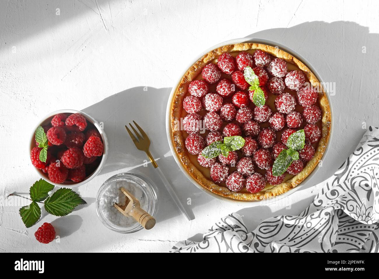 Torta con lampone su sfondo bianco. Cuocere con frutti di bosco freschi. Dolci fatti in casa. Vista dall'alto. Fuoco selettivo. Luce del sole forte ombra profonda. Foto Stock