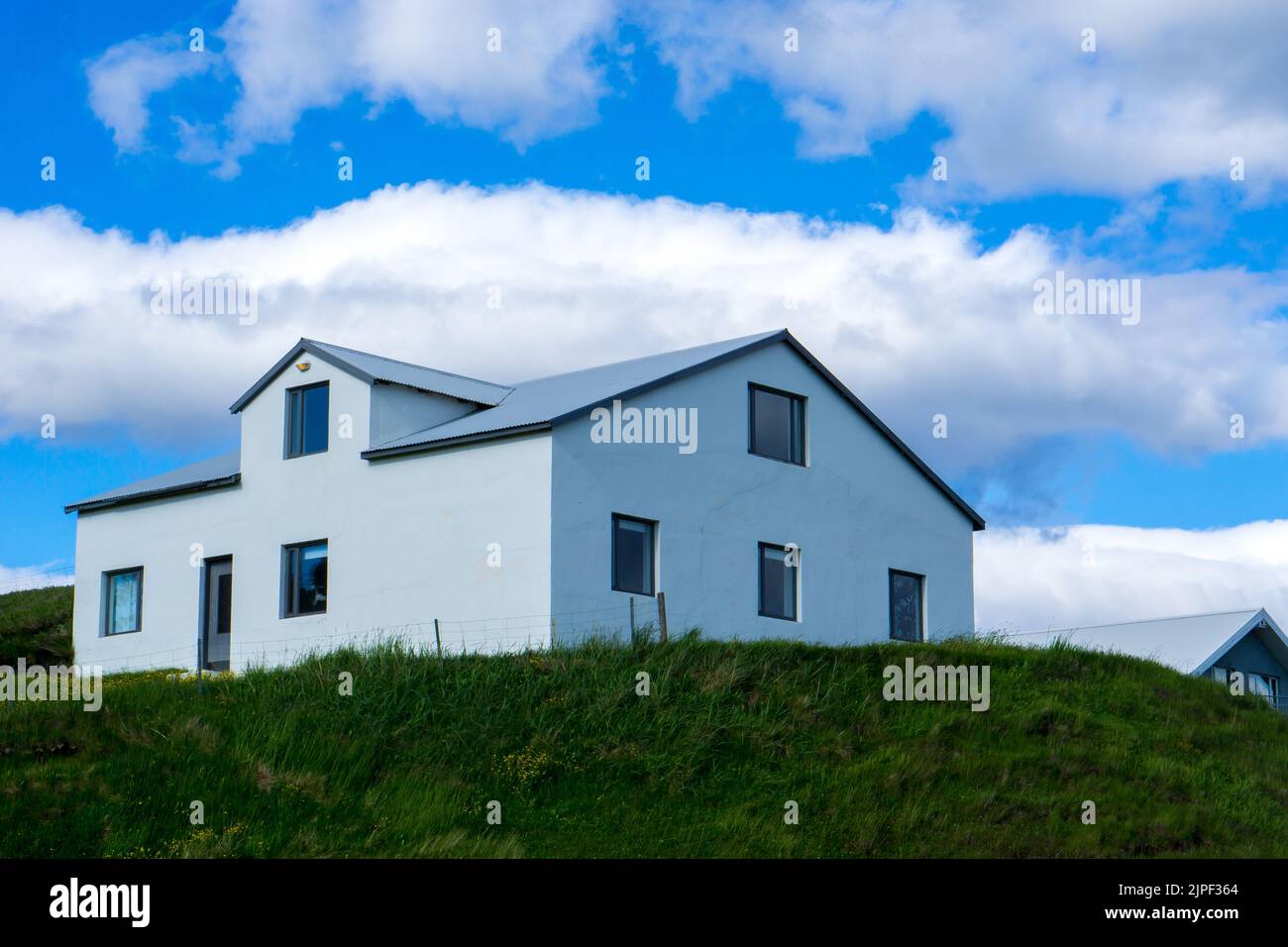 Una bella vista di una casa moderna bianca su una collina verde Foto Stock