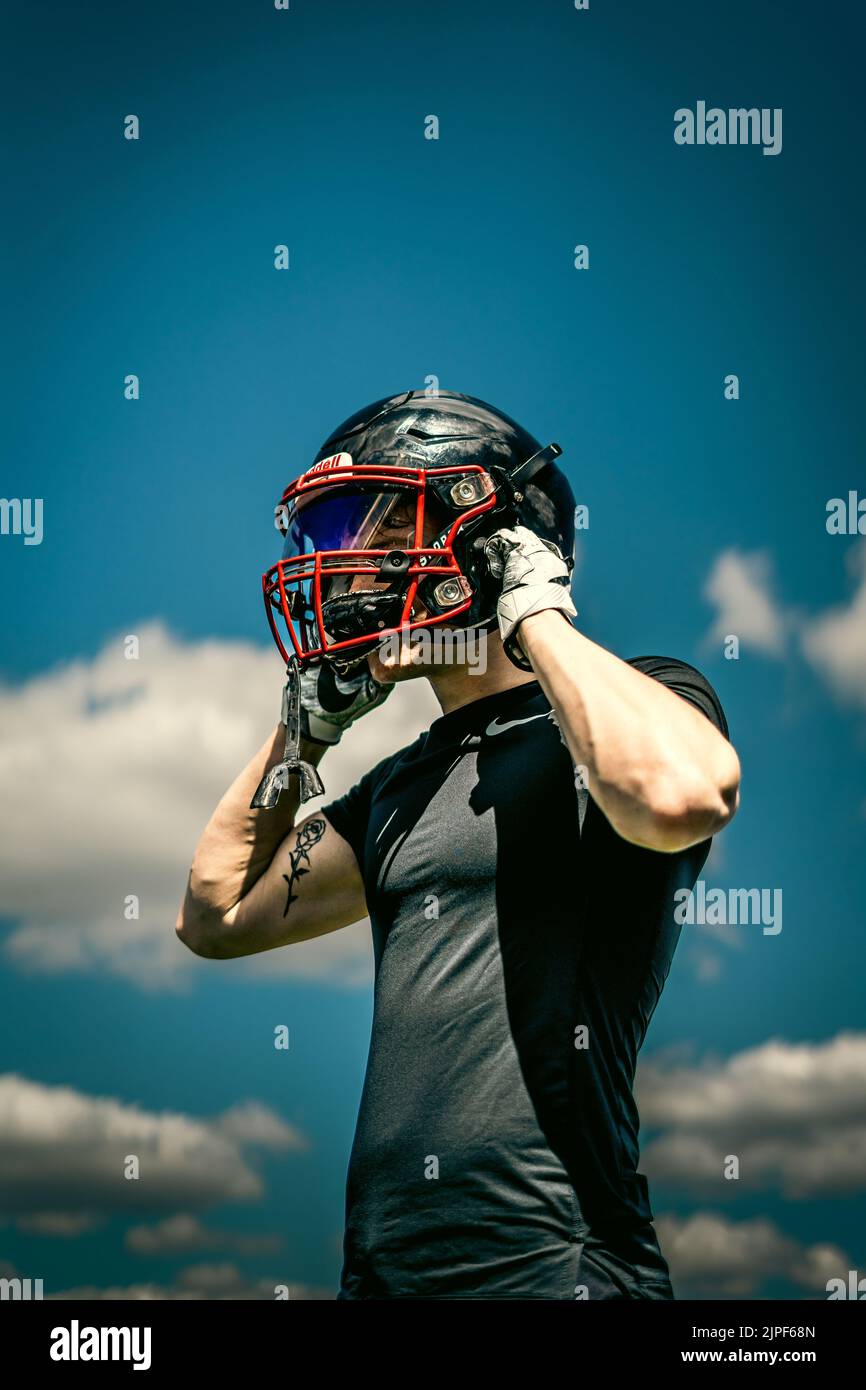 Un calciatore americano che mette il casco sulla sua testa Foto Stock