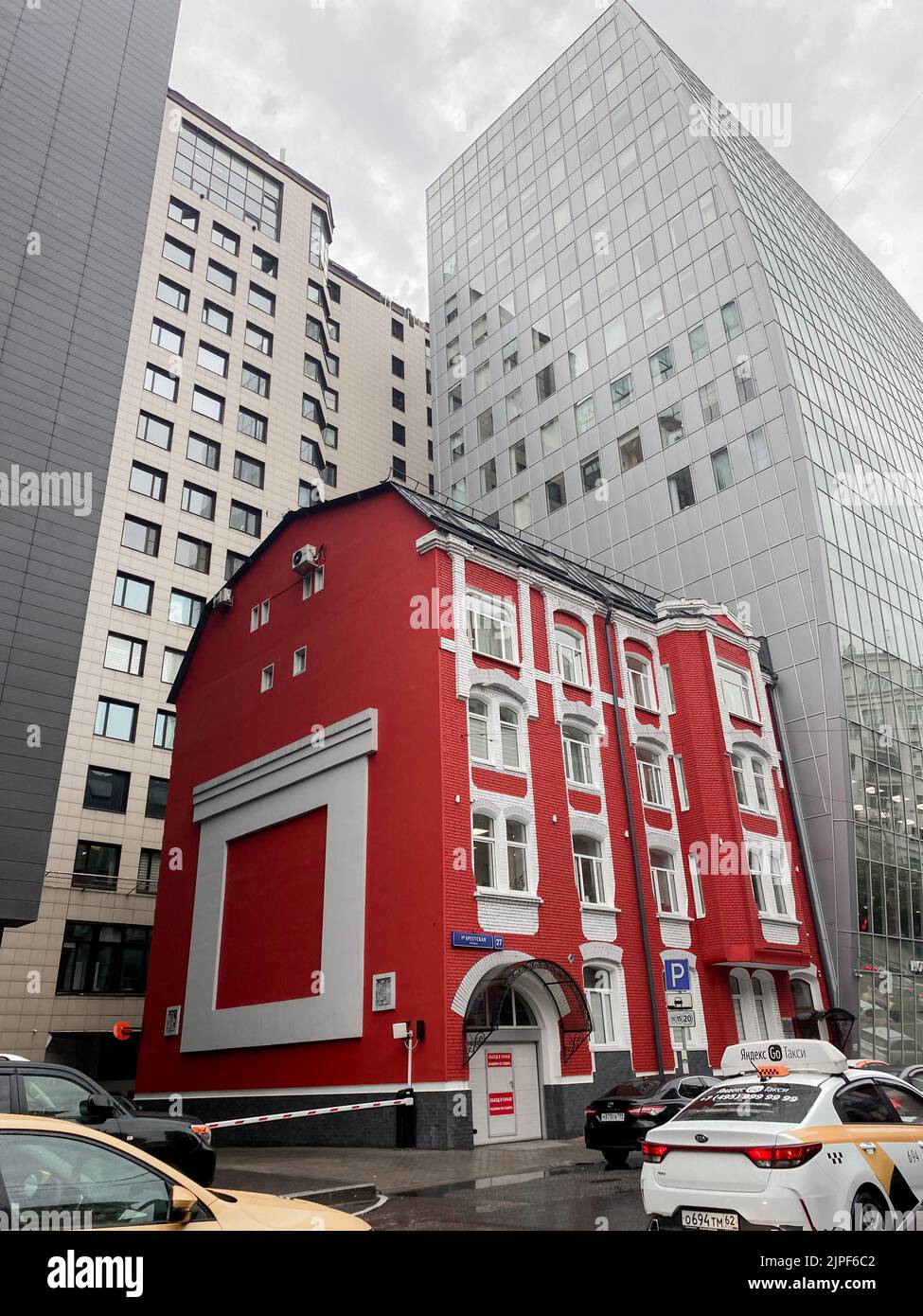 Mosca, Russia, 2021 agosto: Una vecchia casa di mattoni rossi si trova tra enormi grattacieli di vetro grigio. Mix storico e moderno, nuovo e vecchio. Insieme Foto Stock