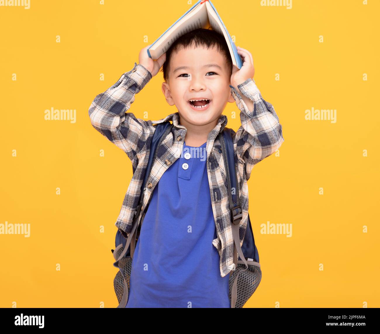 felice ragazzo asiatico tenendo libro sopra la sua testa Foto Stock
