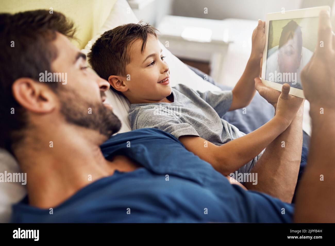 Intrattenimento senza fine grazie alla tecnologia. Un giovane uomo che usa un tablet digitale con suo figlio a casa. Foto Stock