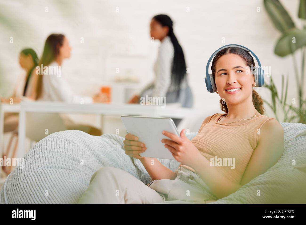 Pensare, ideare e domandarsi alle donne che lavorano e navigano su tablet e cuffie in un ufficio. Felice agenzia di marketing femminile Foto Stock