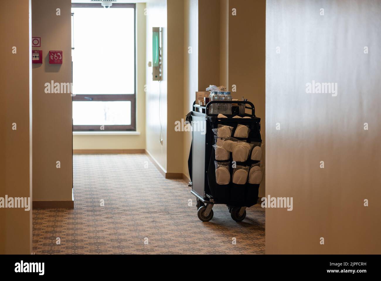 Un carrello per la pulizia utilizzato dalle cameriere in un corridoio deserito dell'hotel Foto Stock