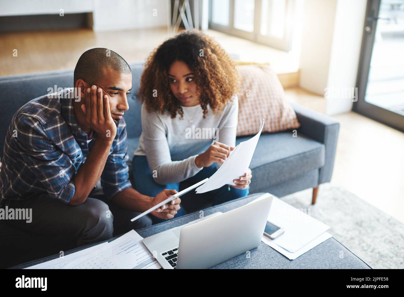 Quando avete speso questo. Una coppia giovane sollecitata che siede insieme e che usa un laptop per andare sopra i loro documenti finanziari. Foto Stock