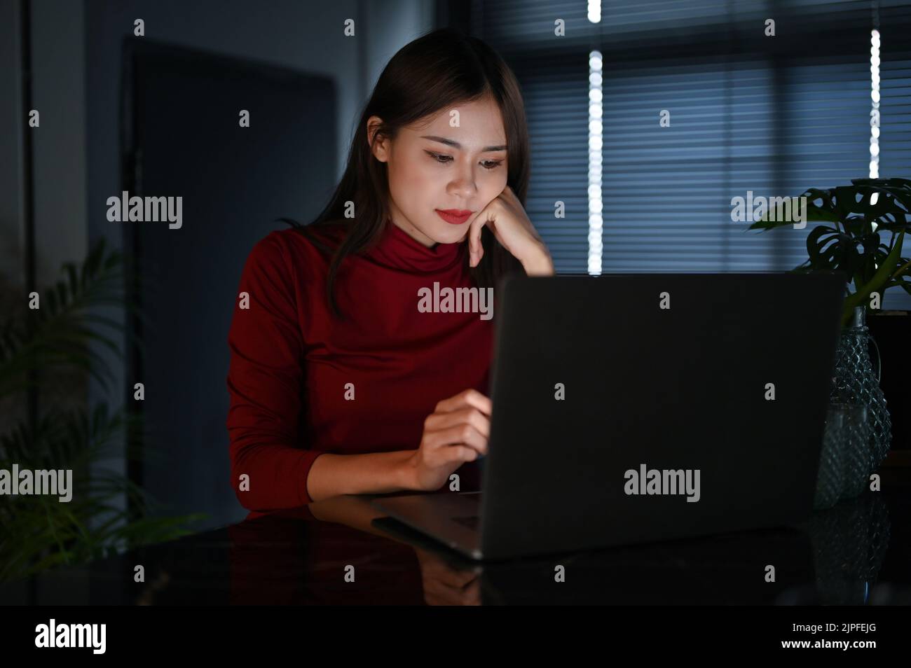Giovane donna d'affari asiatica di talento e duro lavoro o dipendente di ufficio femminile che lavora in ufficio di notte. Foto Stock