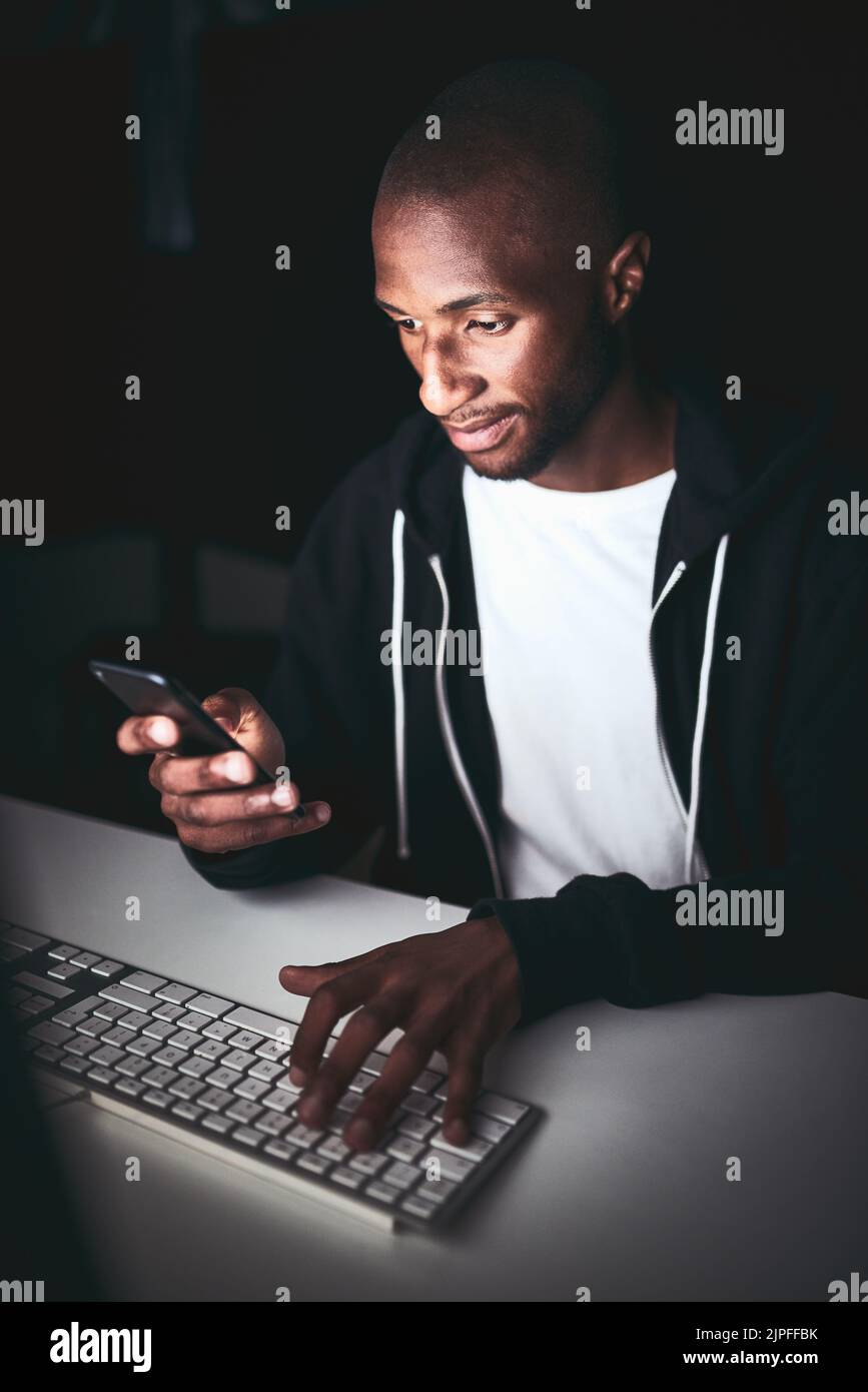 Invio di un aggiornamento del progetto. Scatto ad angolo alto di un giovane uomo che usa il suo cellulare mentre lavora tardi in ufficio. Foto Stock