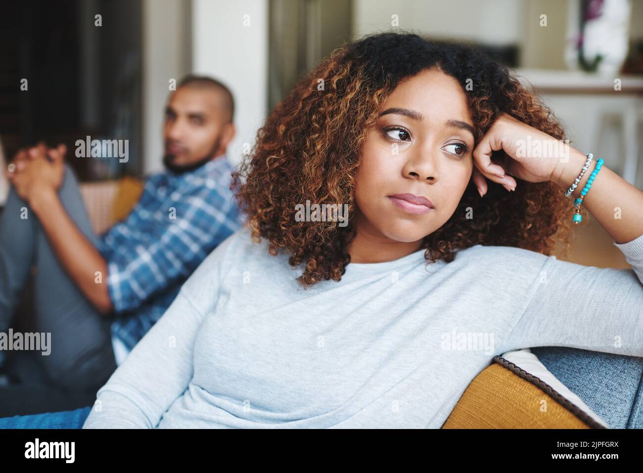 Come supereremo questa situazione: Una giovane donna attraente che si prende cura di un argomento con suo marito nella loro casa. Foto Stock
