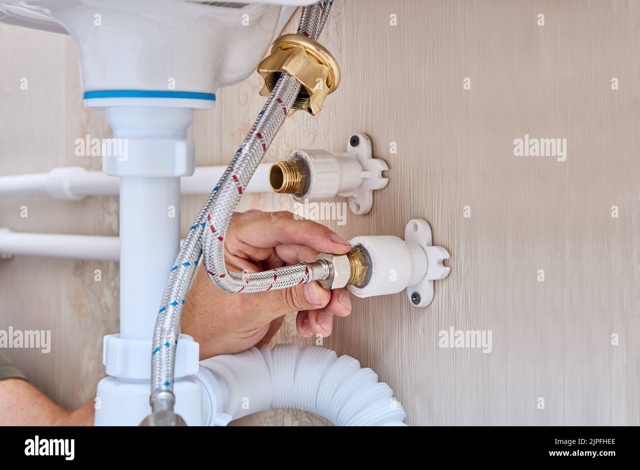 Rubinetto di collegamento sul lavandino in bagno con impianto idraulico domestico. Foto Stock