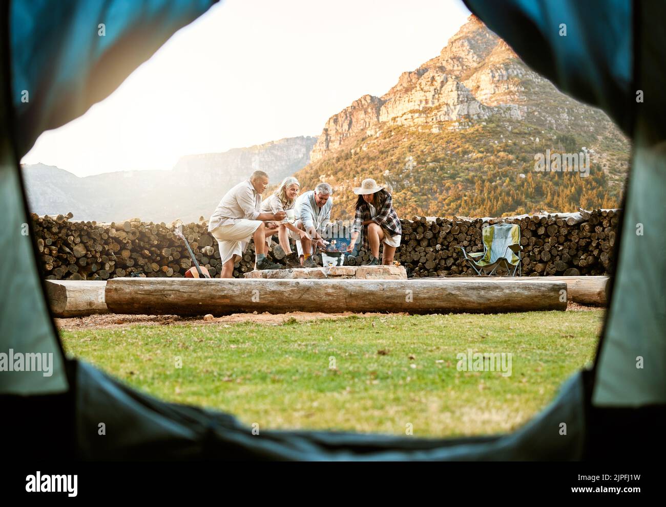 Le persone che accampano con una tenda e marshmallows arrosto su un fuoco da campeggio godono all'aperto, la natura e la natura selvaggia. Aria fresca, avventura e viaggi lifestyle camper Foto Stock