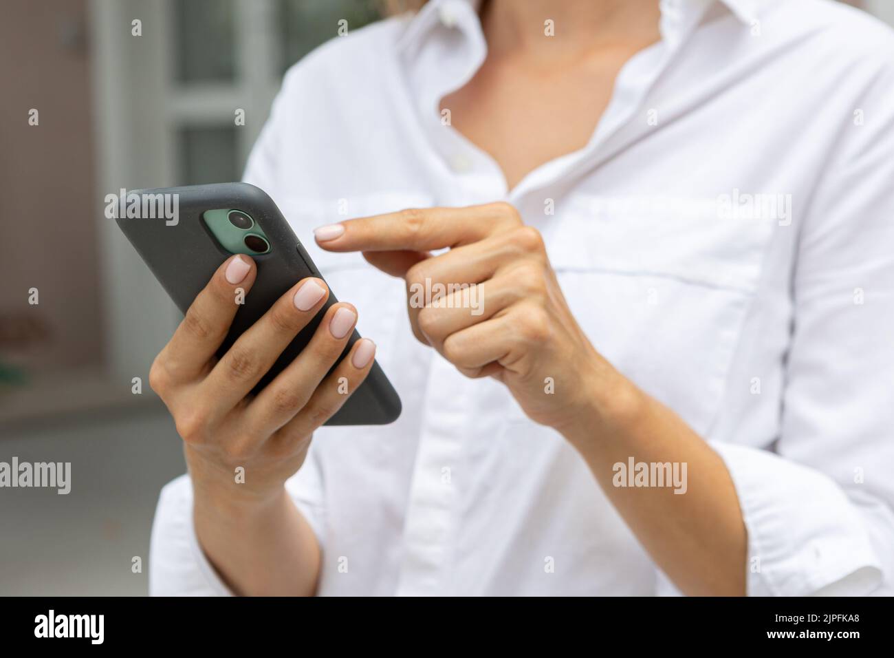 le mani femminili tengono un telefono cellulare moderno per strada. notizie, istruzione, app moderna, ordine di acquisto, lavoro online Foto Stock