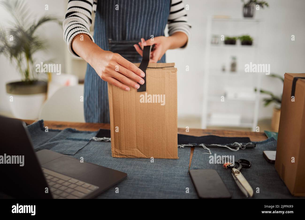 Imballaggio di pacchi, confezioni e ordini di produzione con nastro protettivo durante l'imballaggio, l'imballaggio e l'imballaggio del prodotto. Le piccole imprese possono personalizzare le mani con il notebook e. Foto Stock