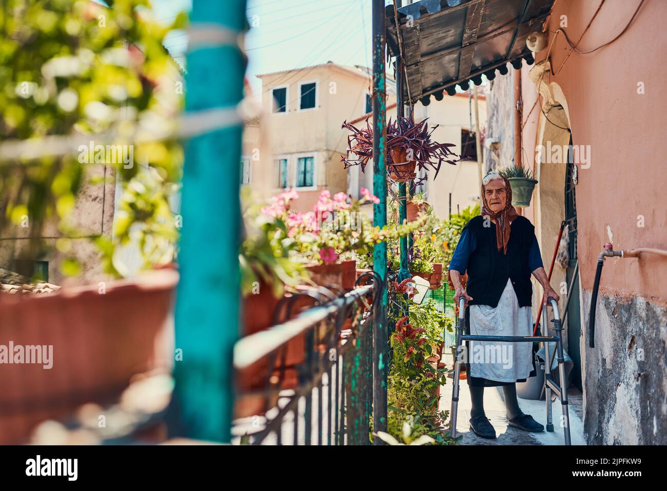 Sono cresciuto in questa stessa casa. Ritratto di una donna anziana in piedi sul suo portico anteriore in una città antica. Foto Stock