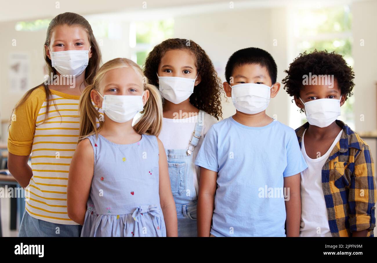 Bambini della scuola, istruzione e covid mentre indossano le maschere del viso in una classe per la protezione contro covid. Ritratto di studenti carini, giovani e intelligenti Foto Stock