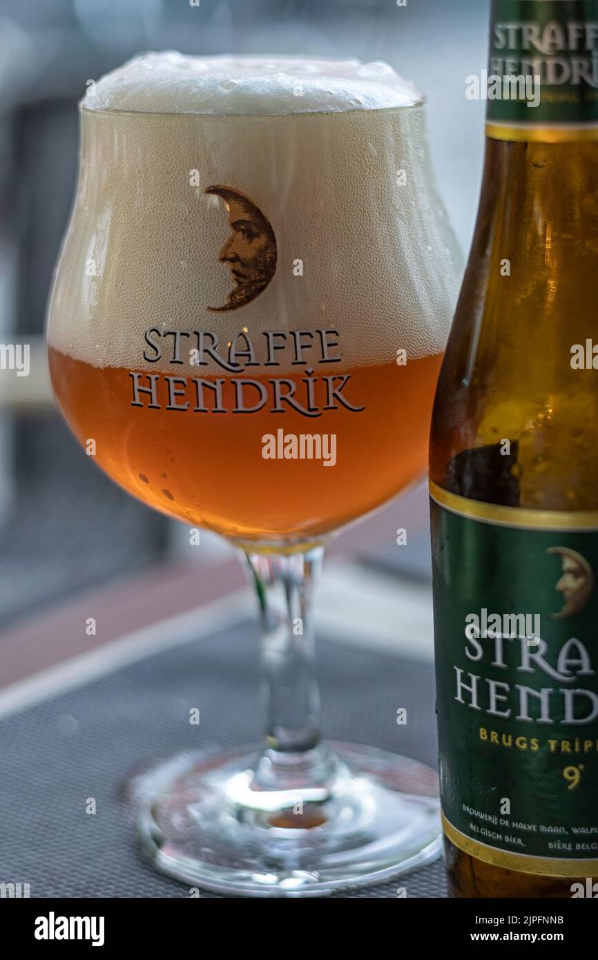 BRUGES, BELGIO - 09 AGOSTO 2022: Bicchiere di birra Straffe Hendrik Triple Blonde in bicchiere di birra su un tavolo in un bar Foto Stock