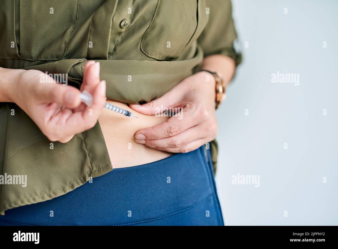 Gestire la sua salute. Colpo di primo piano di una donna d'affari non identificabile che inietta il suo stomaco. Foto Stock