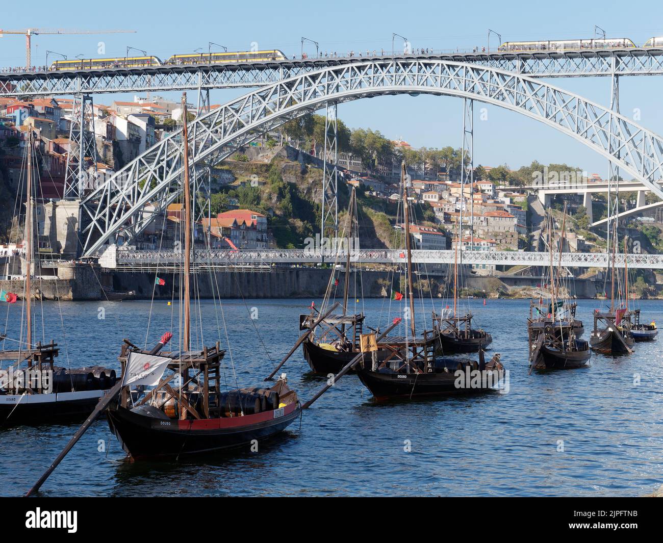Barche tradizionali per il trasporto di vino sul fiume Douro. Un treno della metropolitana attraversa il ponte Luis I. Porto, Portogallo. Foto Stock