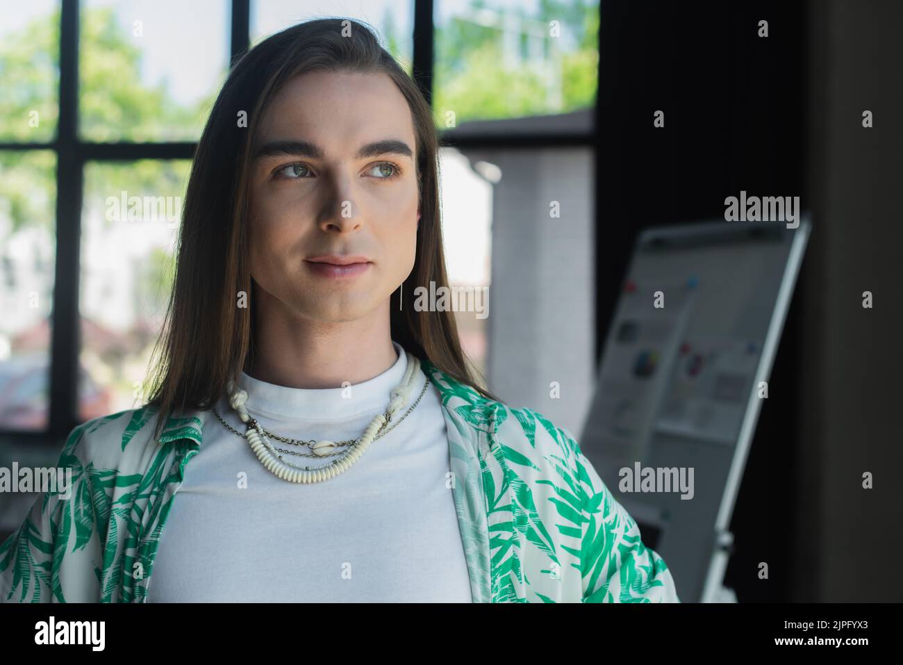 Brunette queer designer guardando lontano in agenzia creativa Foto Stock