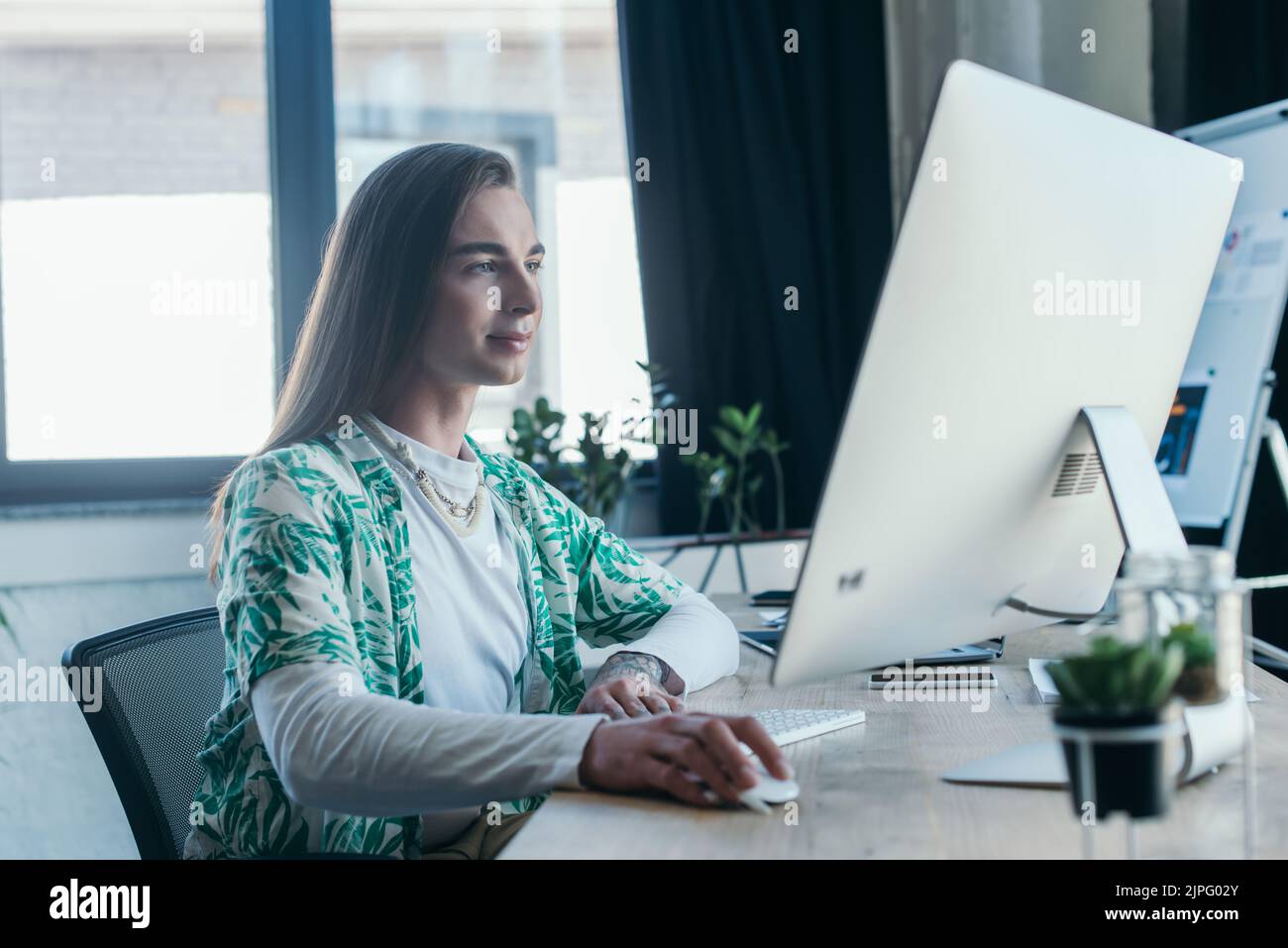 Progettista non binario che utilizza il computer in agenzia creativa Foto Stock