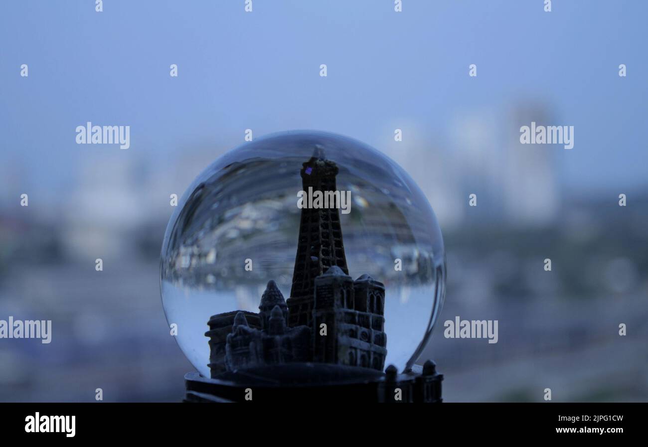 Città giocattolo in un globo di neve sullo sfondo di edifici reali della città Foto Stock