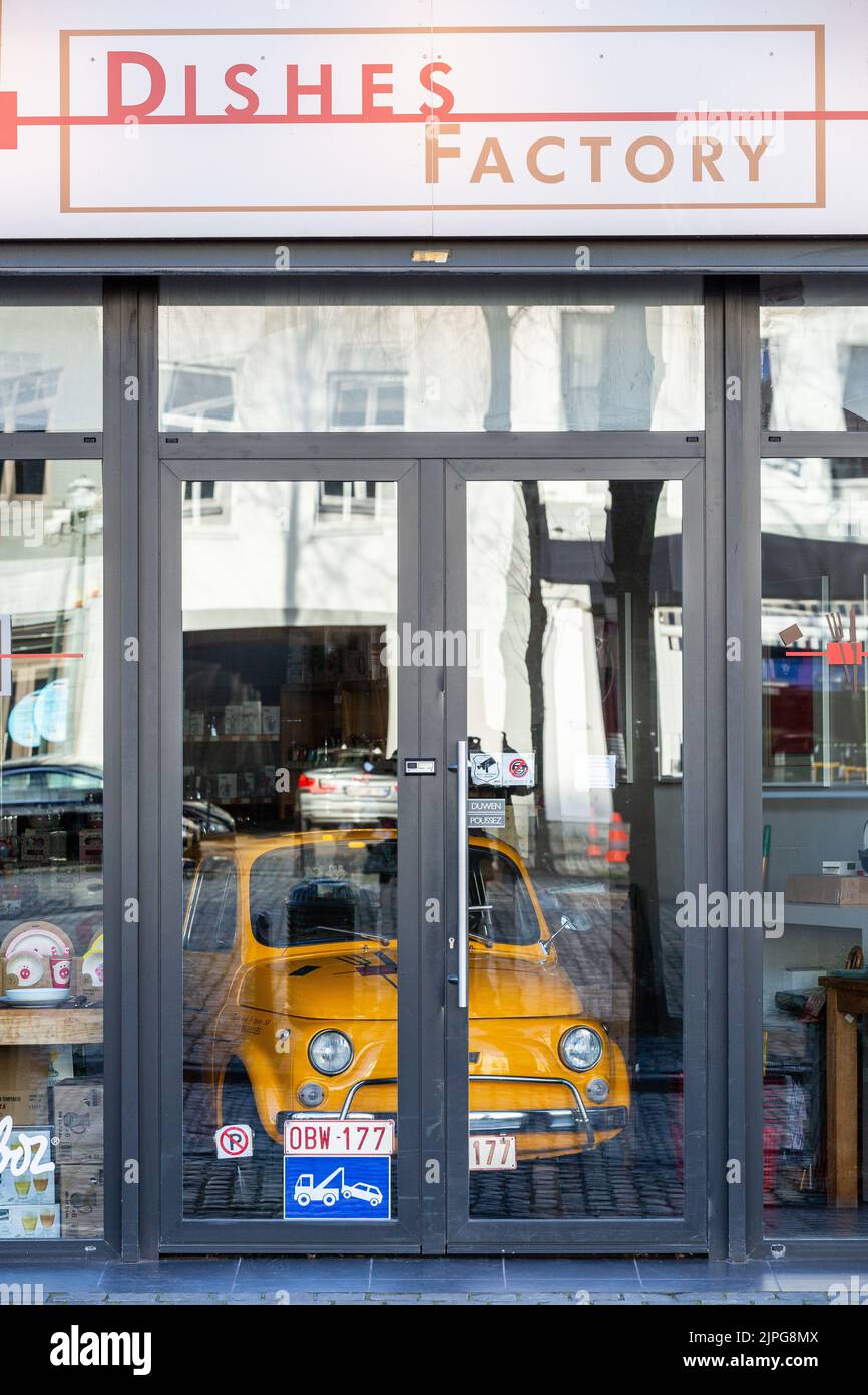 Piccola auto gialla parcheggiata in un negozio di stoviglie chiuso. Foto Stock