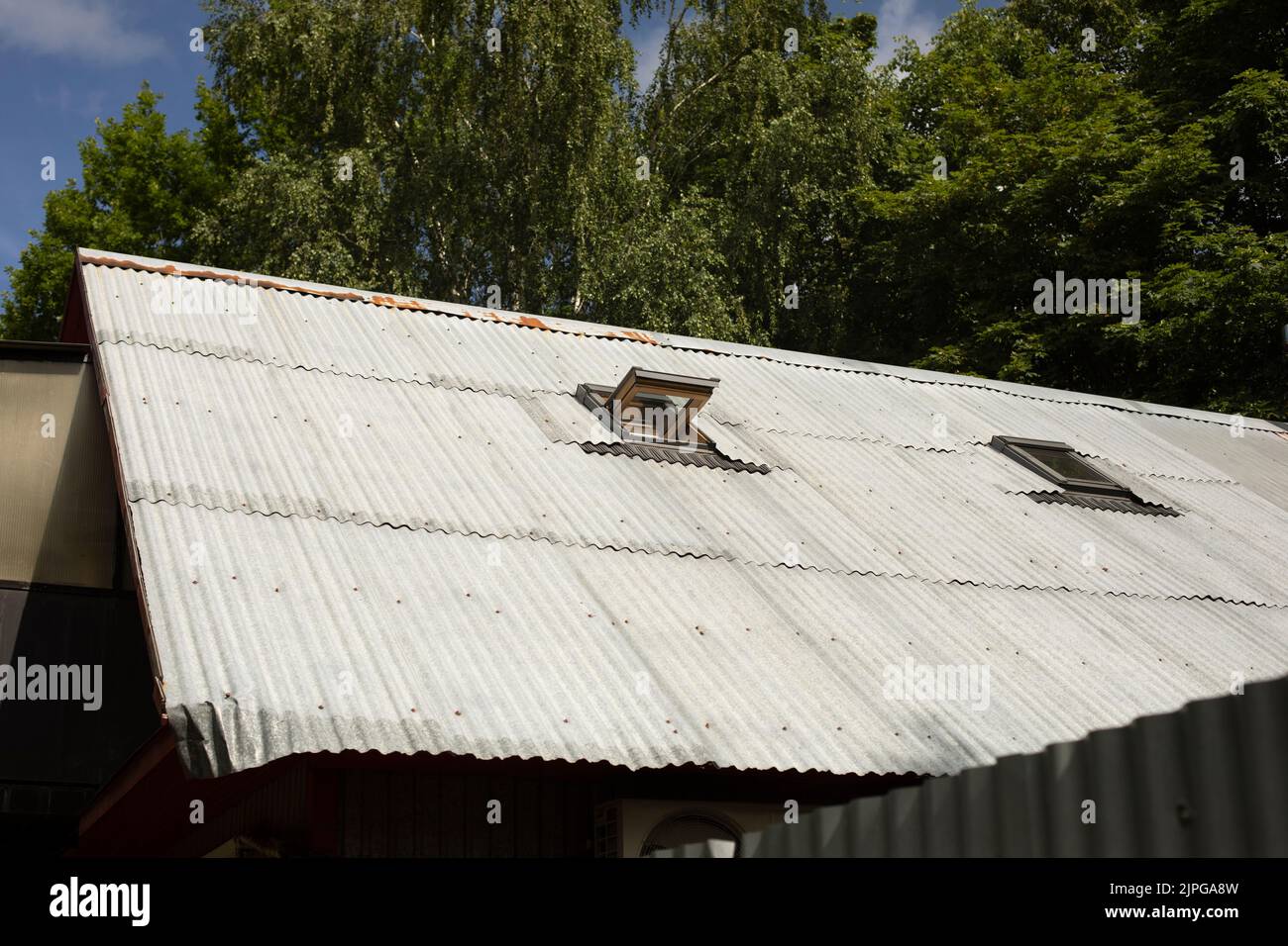 Vecchio tetto di una casa su un piano. Tetto di edificio residenziale in campagna. Dettagli dell'architettura. Finestra aperta in soffitta. Foto Stock