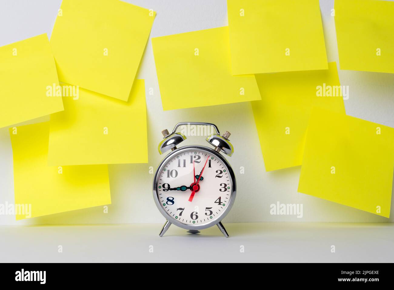 Un orologio con una serie di note adesive gialle che includono obiettivi, promemoria, date importanti o compleanni. È tempo di ricordare le cose Foto Stock