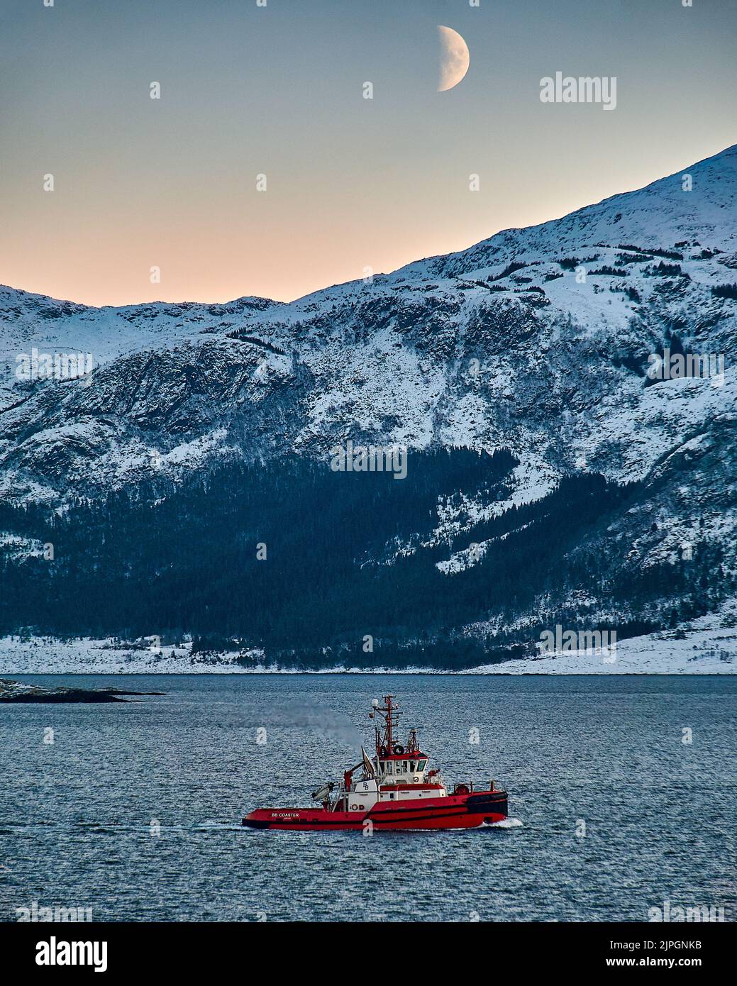 Luna che sorge sopra la montagna su Godøy in inverno, Sunnmøre, Møre og Romsdal, Norvegia. Foto Stock